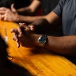 Close-up of arms resting on bar counter, highlighting a wristwatch, creating a relaxed atmosphere.