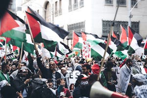 Protesters holding Palestinian flags in a demonstration outdoors, displaying unity and political activism.