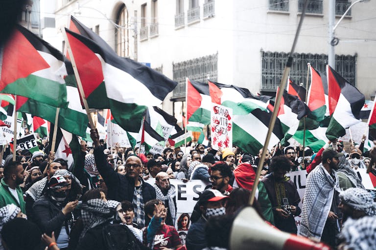 Protesters holding Palestinian flags in a demonstration outdoors, displaying unity and political activism.